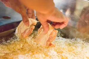 鶏肉にひとつひとつ衣を付ける職人の手